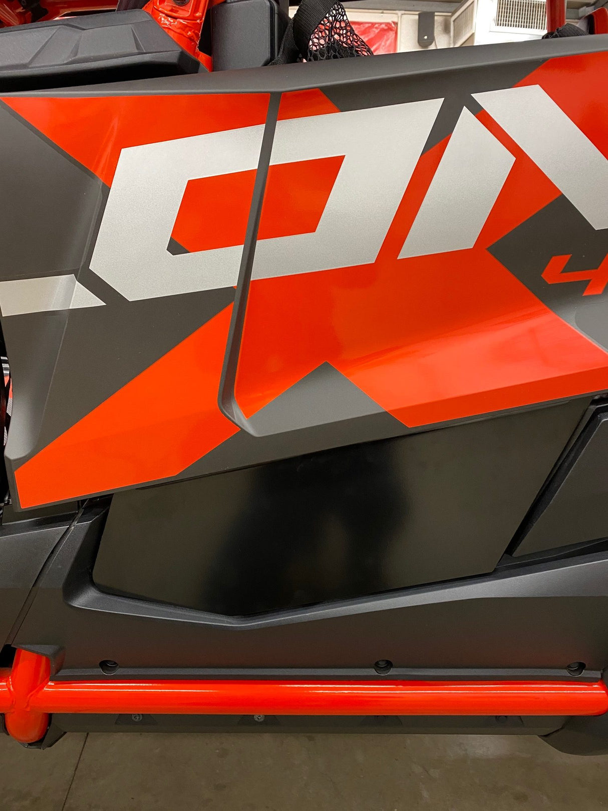 Close-up of the Honda Talon Lower Doors by AJK Offroad, showcasing a bold red and silver geometric design on black. The CNC laser-cut aluminum panel attaches to a strong metal frame, offering stylish durability for off-road adventures.