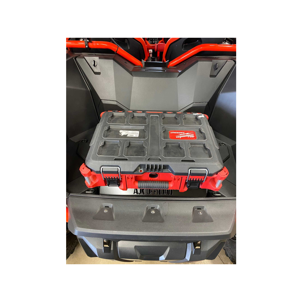A black and red storage box is secured on an ATV with an AJK Offroad Honda Talon Milwaukee Packout Mount. The rugged box has multiple latches and labels, while the vehicle includes a protective red safety bar behind the seat.