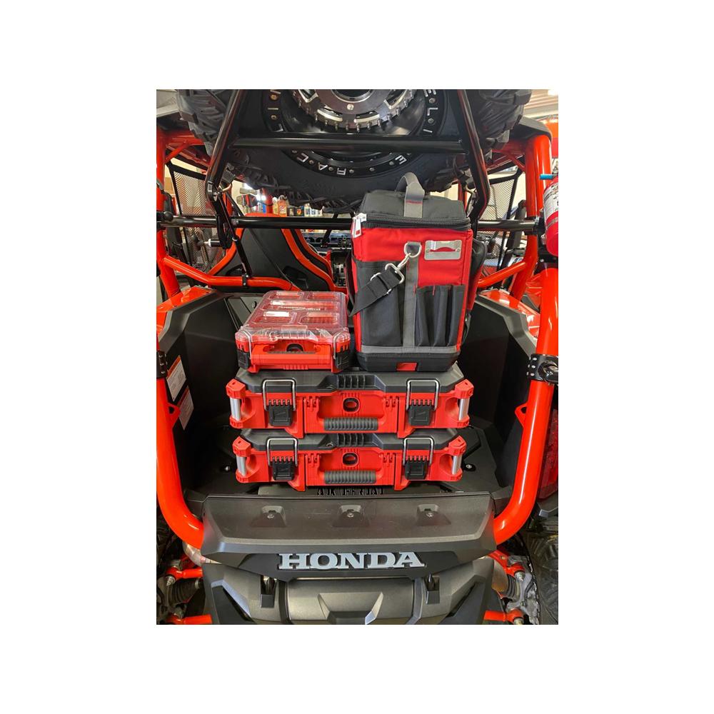 A red Honda utility vehicle carrying a Milwaukee Packout Mount by AJK Offroad showcases neatly organized toolboxes and a tool bag, with parts of the vehicles frame visible.